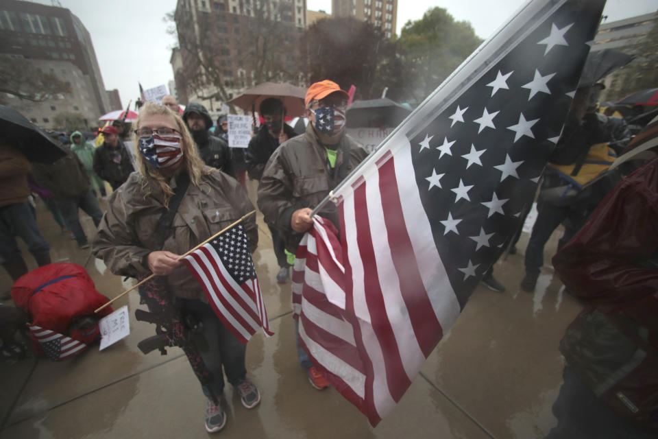 Protesters hold an American flag during a rally against Michigan’s coronavirus stay-at-home order at the State Capitol in Lansing, Mich., Thursday, May 14, 2020. (AP Photo/Paul Sancya)
