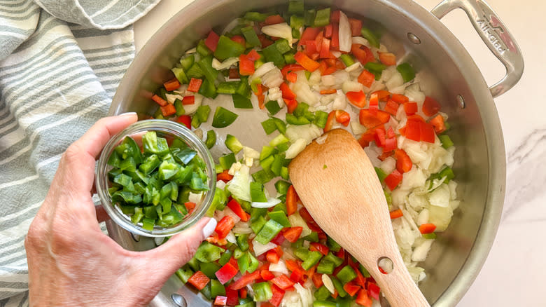 hand adding jalapeno to pan