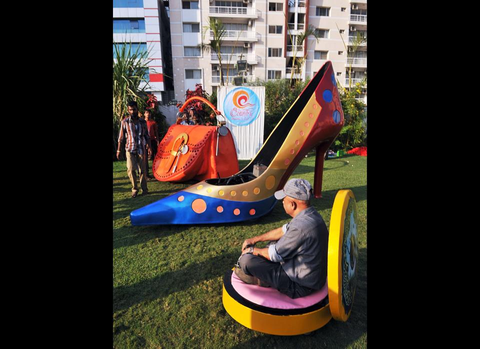 Indian wacky car designer Sudhakar Yadav sits inside a vehicle made in the shape of a makeup compact as other vehicles made in the shapes of a stilletto shoe (C) and a ladies hand bag (L) lay nearby. The vehicles can reach speeds of 28 mph.