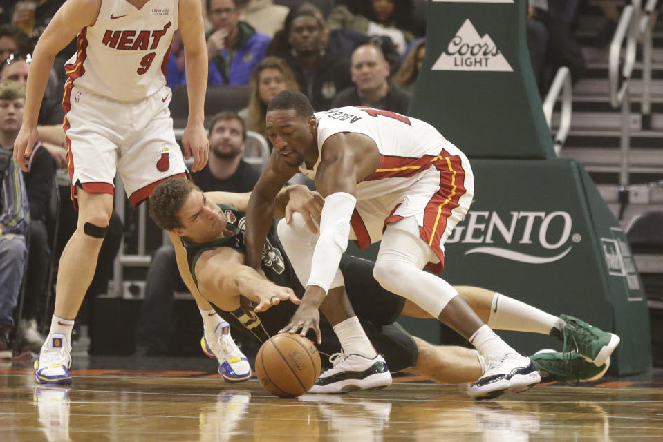 Milwaukee Bucks' Brook Lopez, center, and Miami Heat's Bam Adebayo reach for the ball during the first half of an NBA basketball game Friday, March 22, 2019, in Milwaukee. (AP Photo/Jeffrey Phelps)