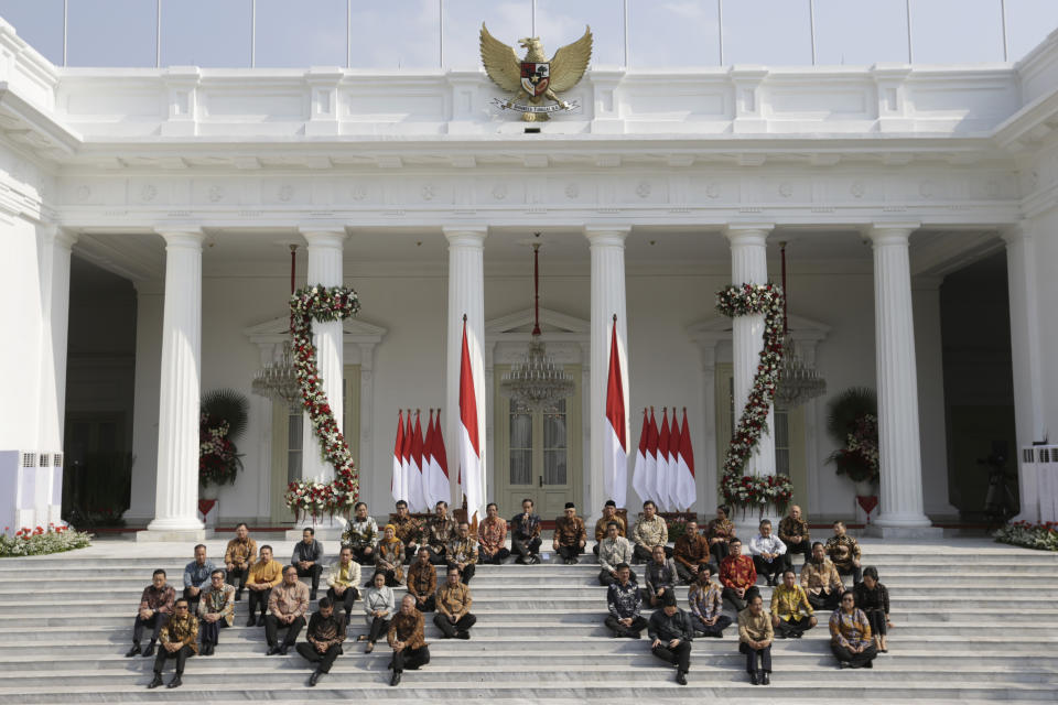 Indonesian President Joko Widodo, top row fifth from left, and his deputy Ma'ruf Amin, sixth from left, sit on the stairs of Merdeka Palace with his new cabinet ministers during the announcement of the new cabinet at in Jakarta, Indonesia, Wednesday, Oct. 23, 2019. (AP Photo/Dita Alangkara)