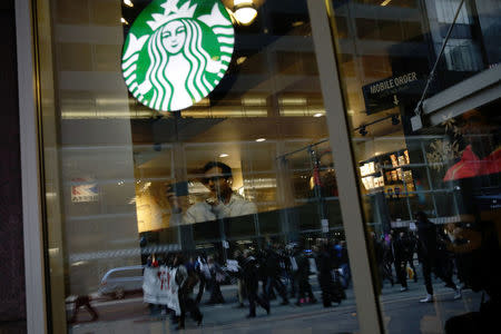 Protesters marching down Market Street are seen reflected in a Starbucks storefront in Philadelphia, a week after two black men were arrested at a Starbucks coffee shop, in Philadelphia, Pennsylvania, U.S. April 19, 2018. REUTERS/Dominick Reuter