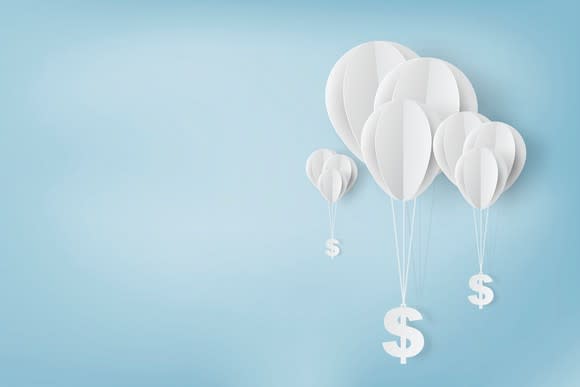 Paper art of balloons carrying dollar signs.