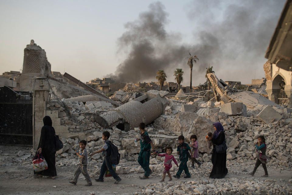 <p>Fleeing Iraqi civilians walk past the heavily damaged al-Nuri mosque as smoke rises in the background in the Old City of Mosul, Iraq, Tuesday, July 4, 2017. (Photo: Felipe Dana/AP) </p>