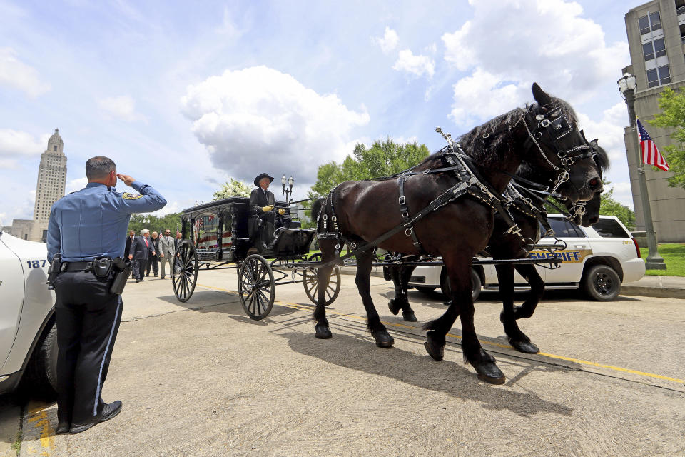 Members of law enforcement from all over the state line the route as a horse-drawn carriage carries former Louisiana Governor Edwin Edwards away from the Louisiana State Capitol and down North 4th Street in Baton Rouge, La., Sunday, July 18, 2021. A processional featuring a law enforcement motorcade and the Southern University Marching Band was held though the streets of downtown Baton Rouge, ending at the Old State Capital building where a private funeral service was held. The colorful and controversial four-term governor died of a respiratory illness on Monday, July 12th at the age of 93. (AP Photo/Michael DeMocker)