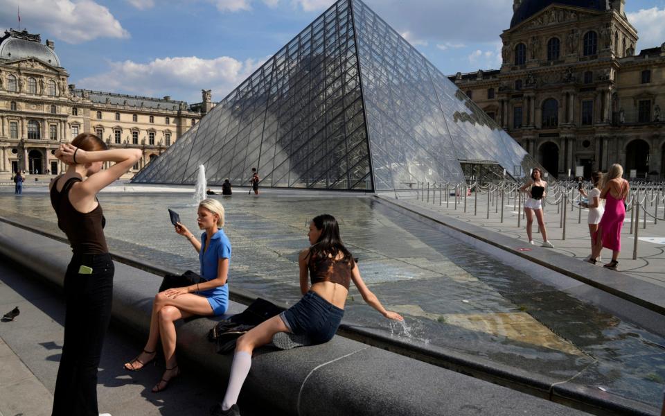 Visitors take a break outside the Louvre Museum courtyard, in Paris, Wednesday, June 9, 2021. France is back in business as a tourist destination after opening its borders Wednesday to foreign visitors who are inoculated against the coronavirus with vaccines approved by the European Union's medicines agency. - AP