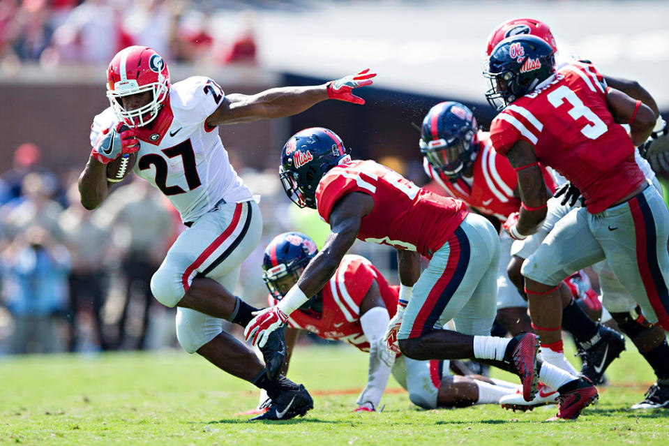 OXFORD, MS - SEPTEMBER 24: Nick Chubb #27 of the Georgia Bulldogs runs the ball and is pursued by the defense of the Mississippi Rebels at Vaught-Hemingway Stadium on September 24, 2016 in Oxford, Mississippi. The Rebels defeated the Bulldogs 45-14. (Photo by Wesley Hitt/Getty Images)