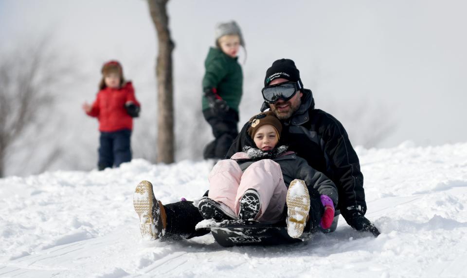 Scott Steele with daughter Lucy, 10, sled the hill Saturday at Veterans Community Park in Plain Township.