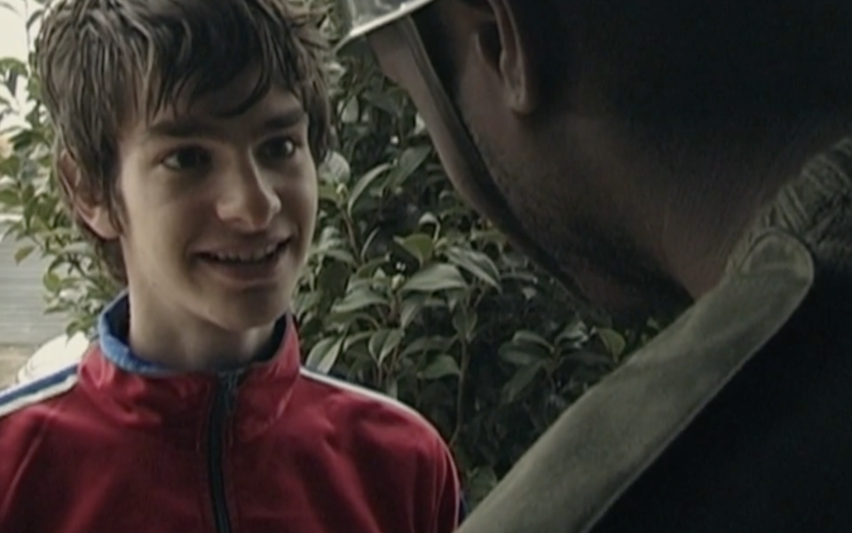 Andrew Garfield stands in a doorway