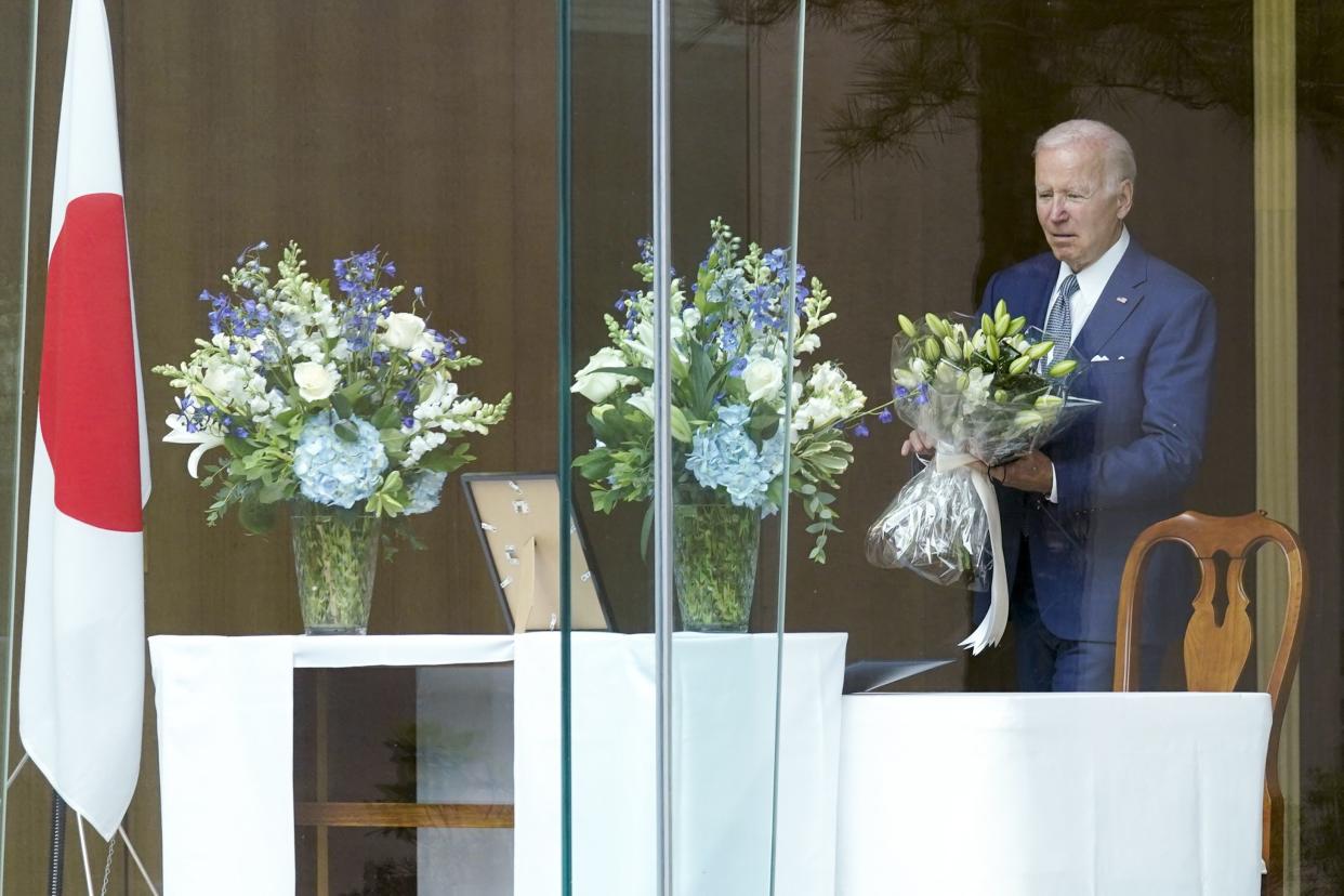 President Biden holds a bouquet as he arrives to sign a condolence book at the Japanese ambassador's residence in Washington on Friday.