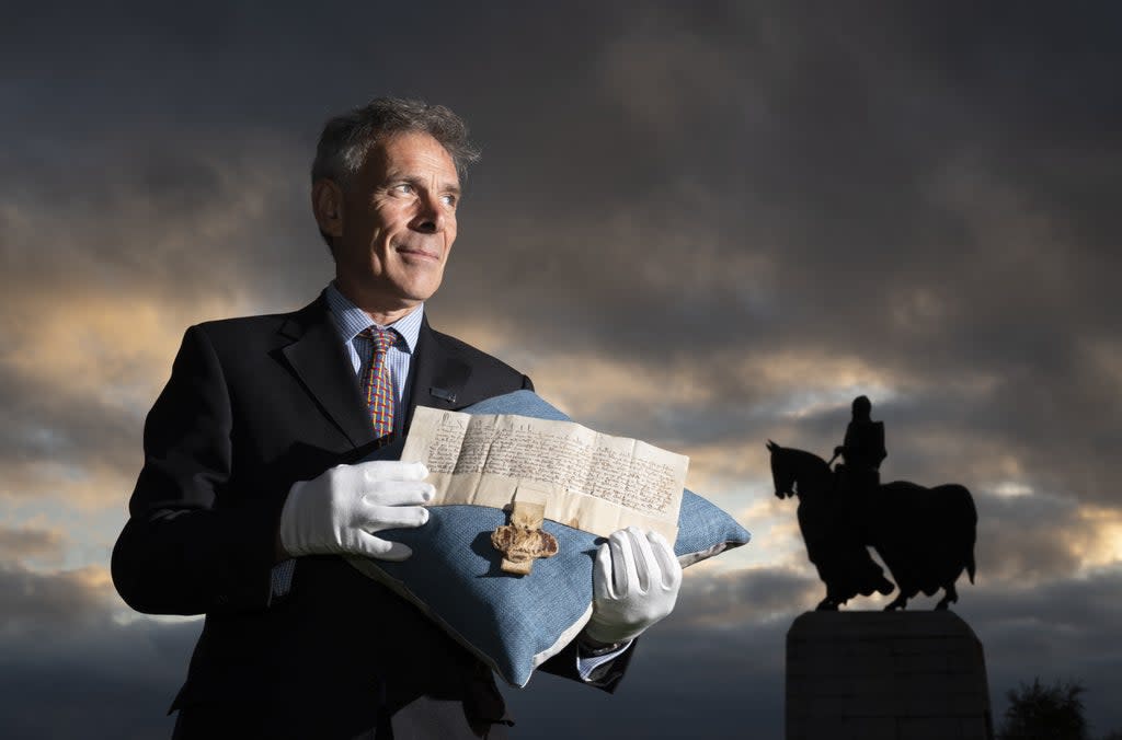 Managing Director of Bonhams Scotland Charles Graham-Campbell holds the Robert the Bruce Letters Patent in his name as King of Scotland alongside the statue of Robert the Bruce at Bannockburn (Jane Barlow/PA) (PA Wire)