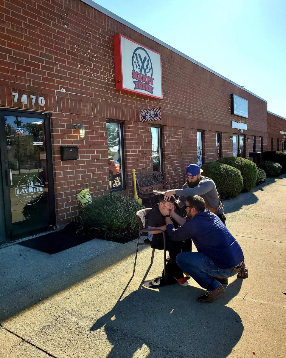 Marco Conti, co-owner of Marky Fresh Barbershop in Mentor, Ohio, cuts Brycen Juby's hair outside after he became overwhelmed in the shop. (Photo: Facebook)