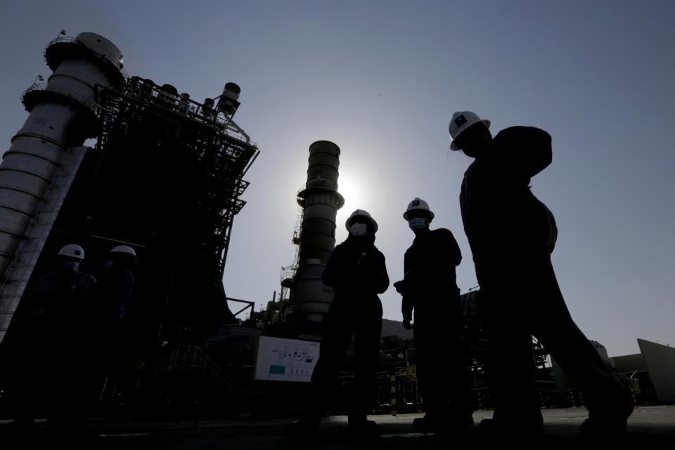 FILE - Saudi Aramco engineers walk in front of a gas turbine generator at Khurais oil field during a tour for journalists, 150 kilometers east-northeast of Riyadh, Saudi Arabia on June 28, 2021. Oil giant Saudi Aramco on Tuesday, Nov. 1, 2022 reported a $42.4 billion profit in the third quarter of this year, buoyed by higher global energy prices. (AP Photo/Amr Nabil, File)