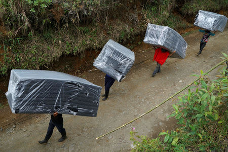 FARC members carry mattresses to their tents in a camp near the transitional zone of Pueblo Nuevo, Colombia, February 4, 2017. REUTERS/Federico Rios