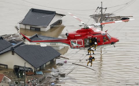 An aerial view shows a local resident being rescued from a submerged house by rescue workers using helicopter at a flooded area in Kurashiki - Credit: Reuters