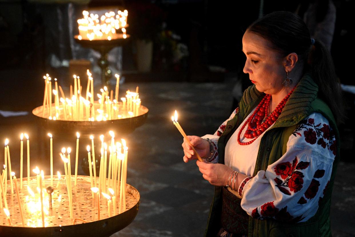 A woman lights a candle during a service at Saints Peter and Paul Garrison Church on the eve of Orthodox Easter in western Ukrainian city of Lviv, on April 15, 2023 (AFP via Getty Images)