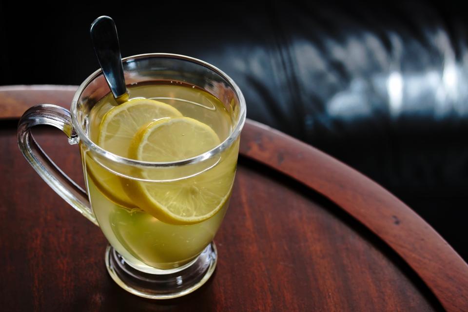 Tasty Hot Toddy with some lemon slices in a glass mug.