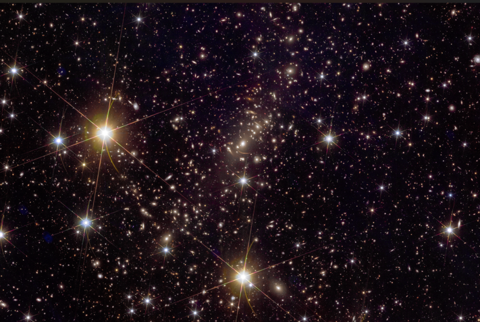 Another dark region of space with many light spots of different sizes.  Diffraction spikes are visible towards the left and bottom of the image and often in some of the larger ones in the periphery.