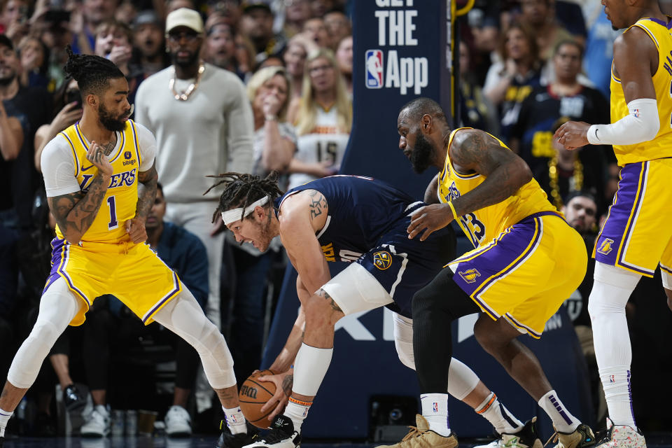 Denver Nuggets forward Aaron Gordon, center, collects a loose ball as Los Angeles Lakers guard D'Angelo Russell, left, and forward LeBron James defend in the second half of Game 5 of an NBA basketball first-round playoff series Monday, April 29, 2024, in Denver. (AP Photo/David Zalubowski)