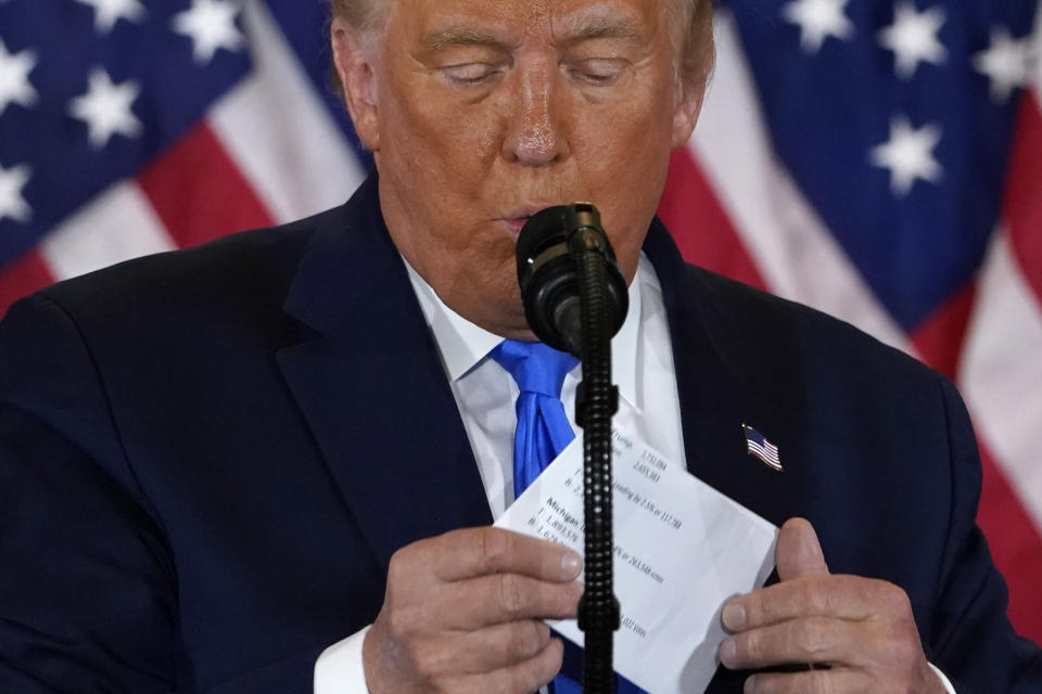 President Donald Trump takes a piece of paper from his suite jacket as he speaks in the East Room of the White House, early Wednesday, Nov. 4, 2020, in Washington. (AP Photo/Evan Vucci)