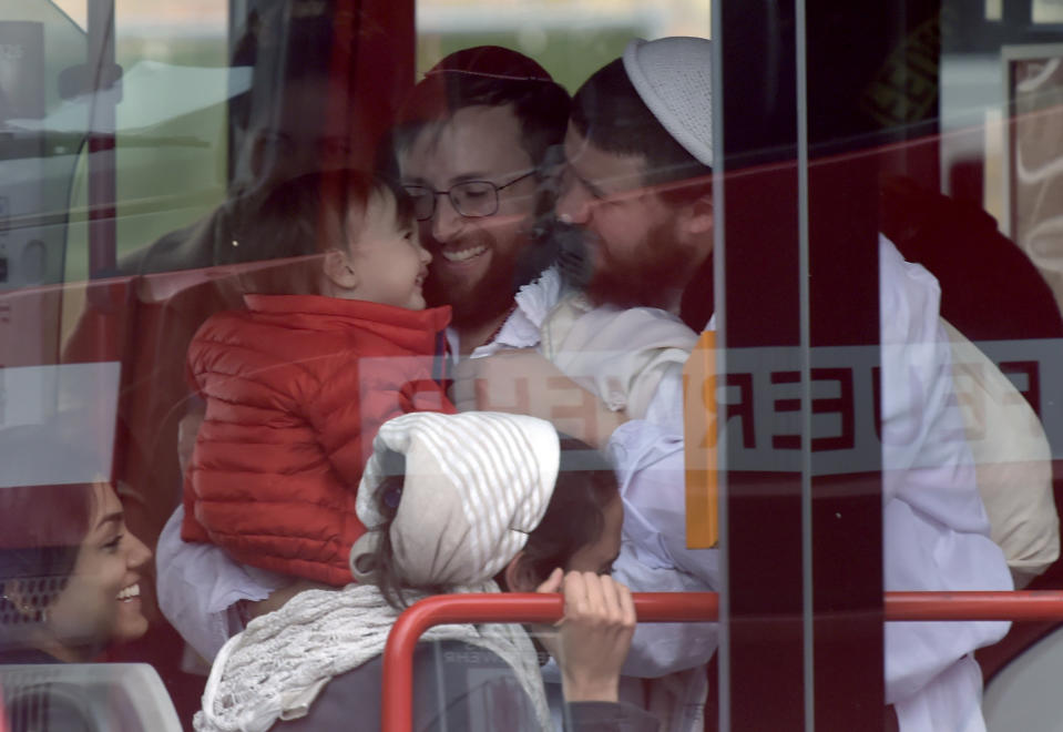 People, wearing traditional Jewish clothing, react after they were escorted to a bus at a Jewish cemetery and synagogue in Halle, Germany, Wednesday, Oct. 9, 2019. One or more gunmen fired several shots on Wednesday in the German city of Halle. Police say a person has been arrested after a shooting that left two people dead. (AP Photo Jens Meyer)