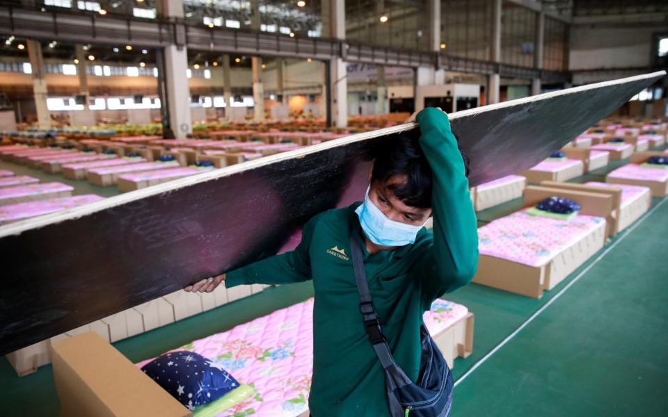 A worker carries a plank as the Thai government converts an air cargo warehouse into a coronavirus field hospital at Don Mueang International Airport in Bangkok, Thailand on 28 July 2021 - Soe Zeya Tun/Reuters