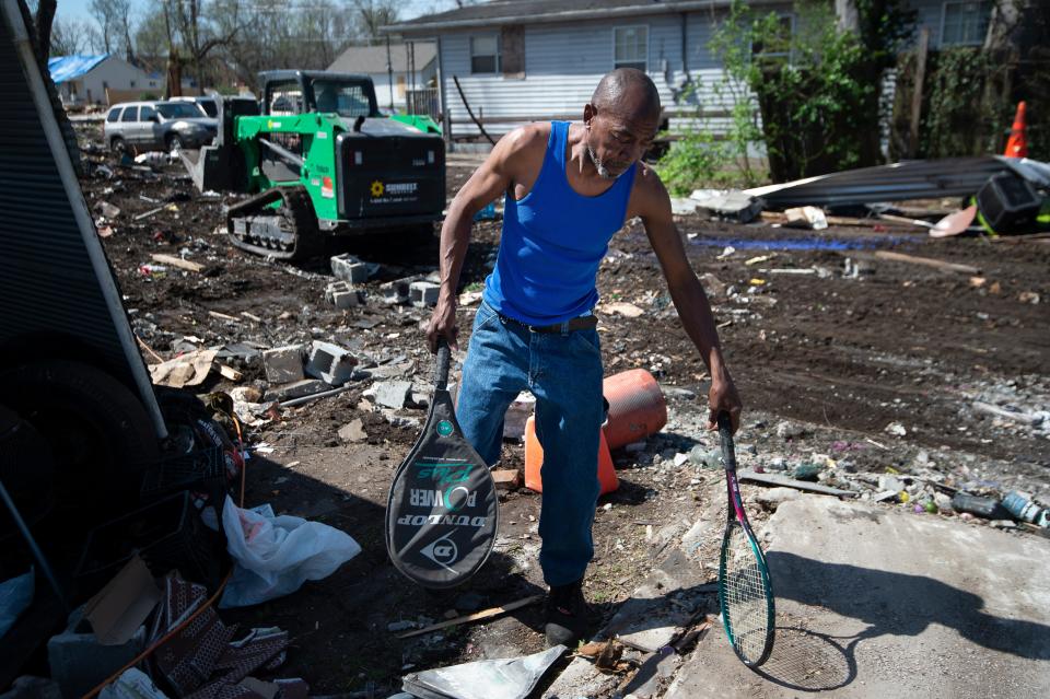 Homeowner Sam Brown picks up belongings as debris from his homesite is removed Thursday, March 26, 2020 in Nashville, Tenn.