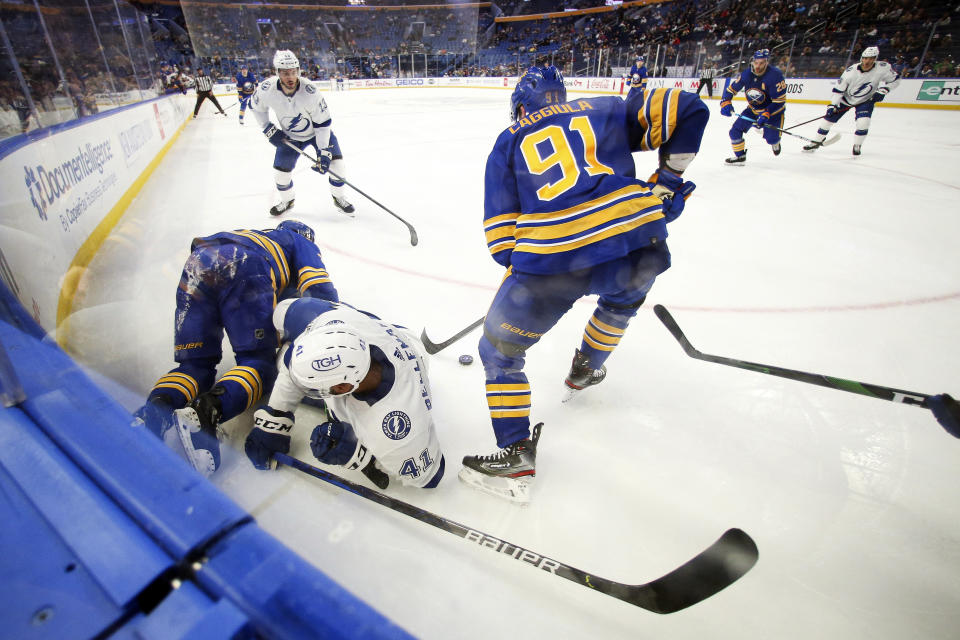 Buffalo Sabres center Drake Caggiula (91) gets control of the puck after right wing Kyle Okposo (21) and Tampa Bay Lightning left wing Pierre-Edouard Bellemare (41) collided during the second period of an NHL hockey game Monday, Oct. 25, 2021, in Buffalo, N.Y. (AP Photo/Joshua Bessex)