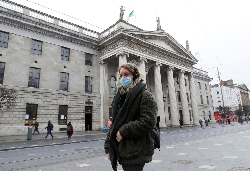 A woman wearing a face mask walks past the GPO on a very quiet O'Connell Street in Dublin's city centre: PA