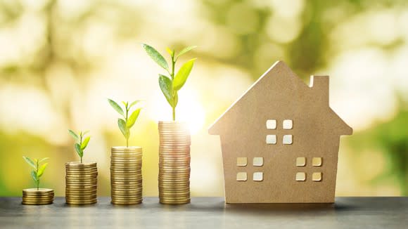 Stacks of coins and a cutout of a home.