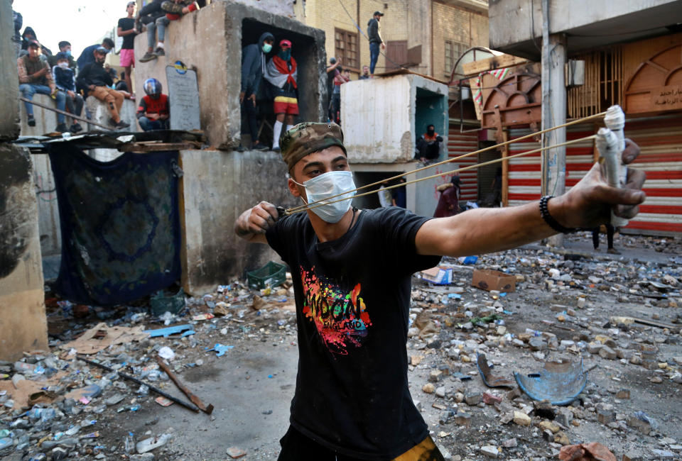 An anti-government protester uses a slingshot to fire stones at riot police during clashes in Baghdad, Iraq, Thursday, Nov. 28, 2019. Scores of protesters have been shot dead in the last 24 hours, amid spiraling violence in Baghdad and southern Iraq, officials said. (AP Photo/Khalid Mohammed)