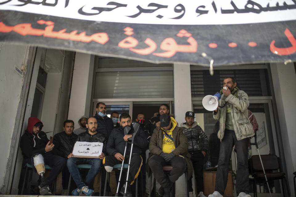 People who were injured during Tunisia's democratic uprising 10 years ago, stage a protest demanding official recognition, in Tunis, Tunisia, Tuesday, Jan. 12, 2021. Banner in Arabic read "We won't celebrate, the uprising continues". As Tunisia this week marks the 10th anniversary of the revolt that unleashed the Arab Spring, those injured in the tumult feel disappointed and marginalized. Since December, they have been holding a sit-in at the office of the Agency for the Revolutionary Martyrs and Wounded, demanding recognition. (AP Photo/Mosa'ab Elshamy)