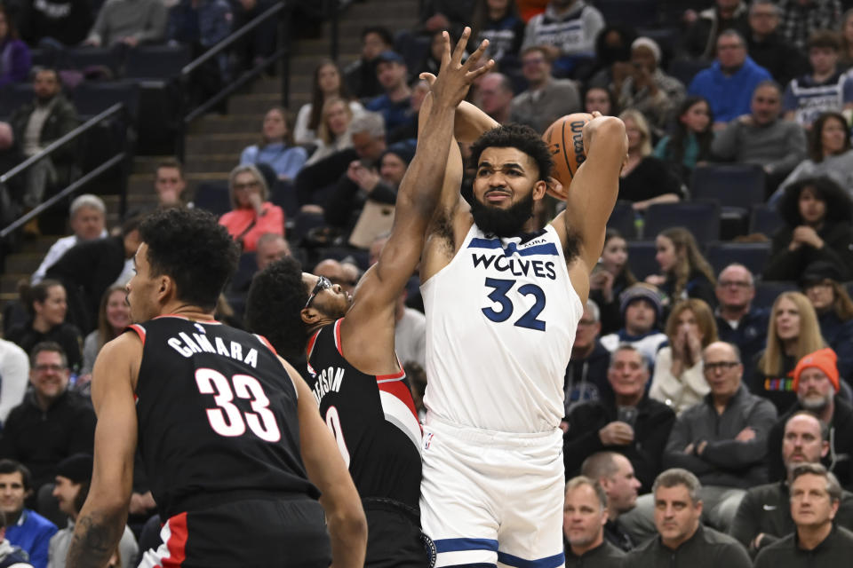 Minnesota Timberwolves center Karl-Anthony Towns (32) looks to pass the ball while defended by Portland Trail Blazers guard Scoot Henderson during the first half of an NBA basketball game Friday, Jan. 12, 2024, in Minneapolis. (AP Photo/Craig Lassig)