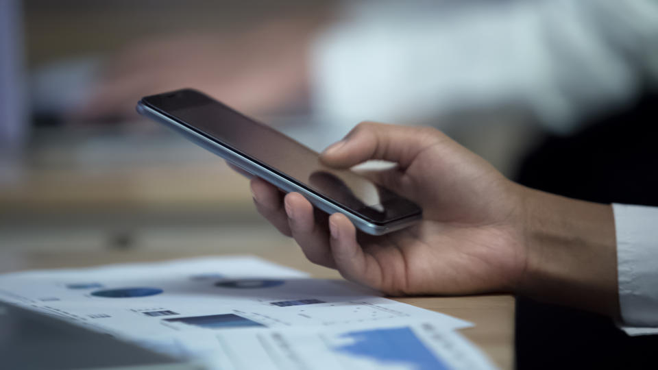 Office worker using smartphone while observing charts, modern technologies, stock footage