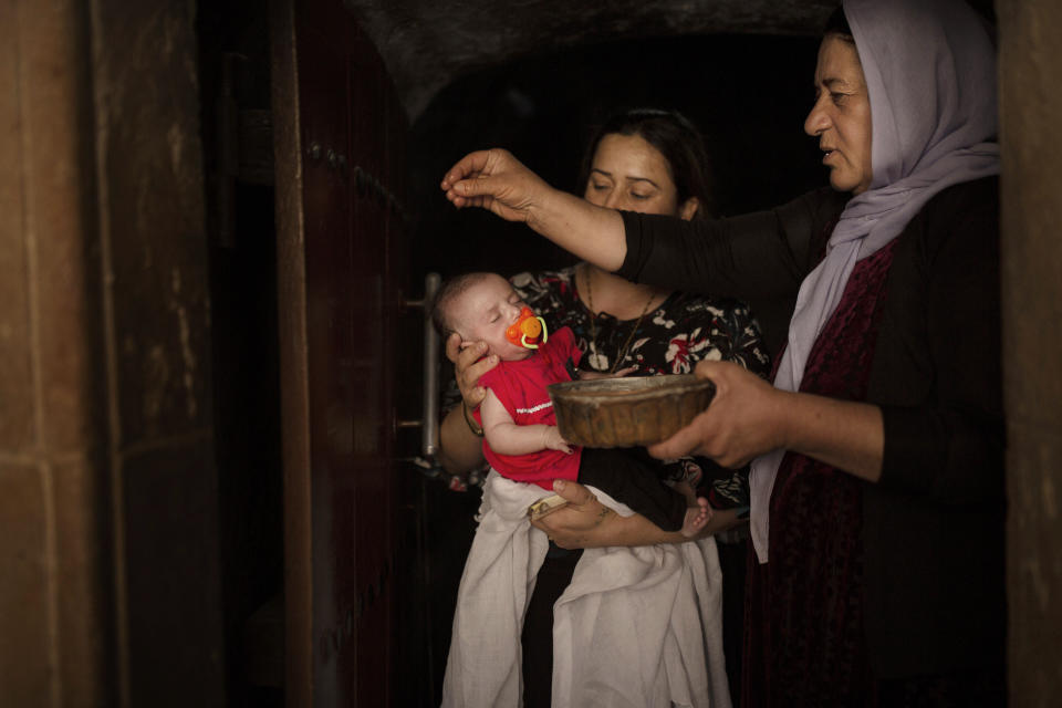 In this Aug. 23, 2019 photo, a baby girl is annointed with water from an ancient spring by a Yazidi holy woman at the the Lalish temple near Sheikhan, Iraq. The ancient sect is rebuilding, nearly six years after Islamic State militants launched its coordinated attack on the heartland of the Yazidi community at the foot of Sinjar Mountain in August 2014. (AP Photo/Maya Alleruzzo)