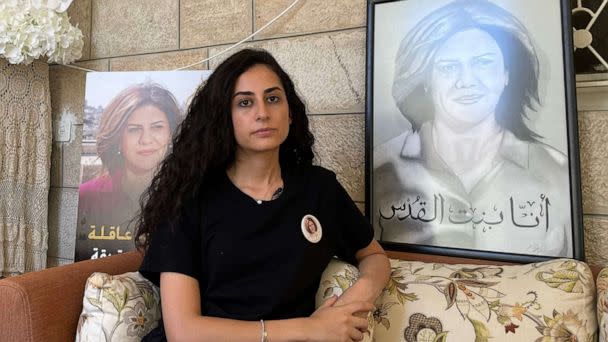PHOTO: Lina Abu Akleh, the niece of slain Al Jazeera journalist Shireen Abu Akleh, sits surrounded by photographs of her late aunt, at the family home in occupied east Jerusalem, on July 13, 2022. (Rosie Scammell/AFP via Getty Images)