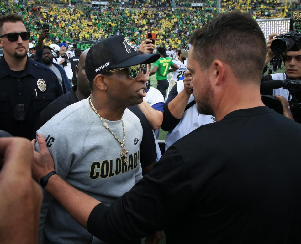 Colorado coach Deion Sanders, left, and Oregon's Dan Lanning meet at midfield after the game at Autzen Stadium.