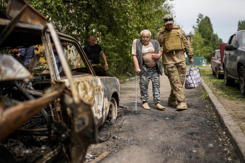 A volunteer helps a man leaving his home in a building damaged by an overnight missile strike, in Sloviansk, Ukraine, Tuesday, May 31, 2022. (AP Photo/Francisco Seco)