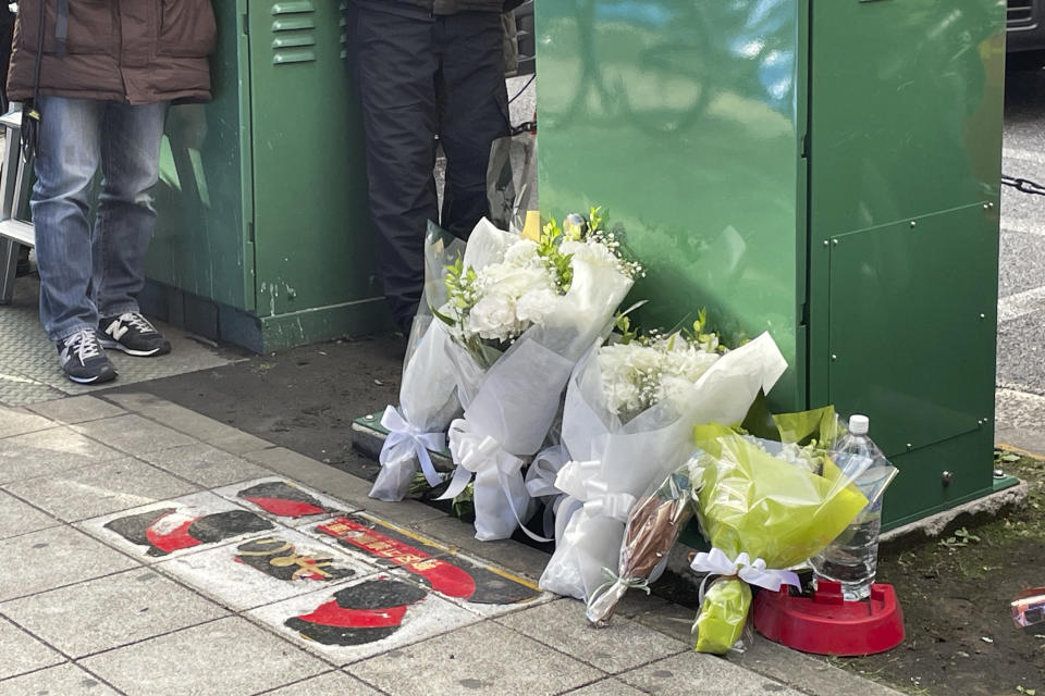 Flowers and drinks are placed in front of a building where a fire broke out Friday in Osaka, western Japan, Saturday, Dec. 18, 2021. Japanese police on Saturday searched the house of one of the patients at a mental clinic where the fire gutted an entire floor in the eight-story building, killing over 20 people trapped inside. (AP Photo/Chisato Tanaka)