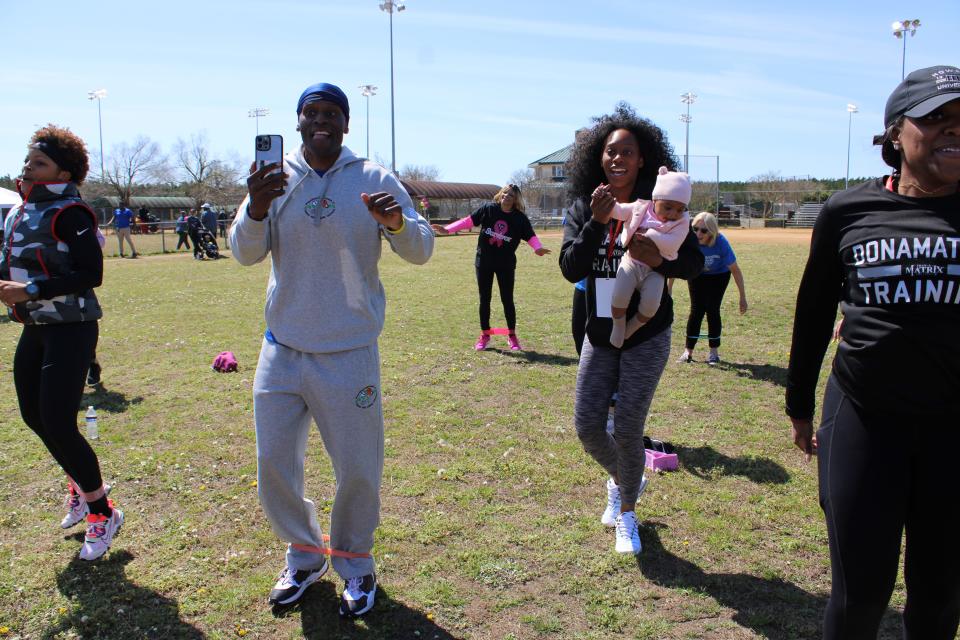 Wearing grey, DB Donamatrix uses his signature resistance band at Donamatrix Day 2022 in Petersburg, Va. His daughter Tuesdae and infant granddaughter Winter joined him.