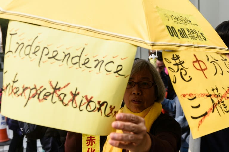 A woman holds an umbrella with a sign that reads 'Independence' with the word "Interpretation' crossed out, as she protests in support of elected pro-democracy lawmakers outside Hong Kong's High Court on March 1, 2017