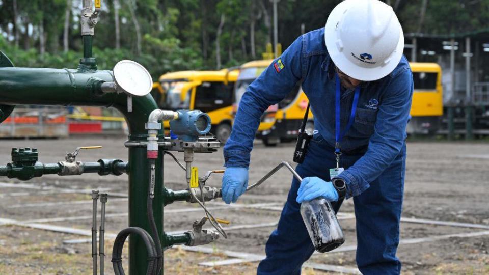 Un operario maneja una válvula de oleoductos