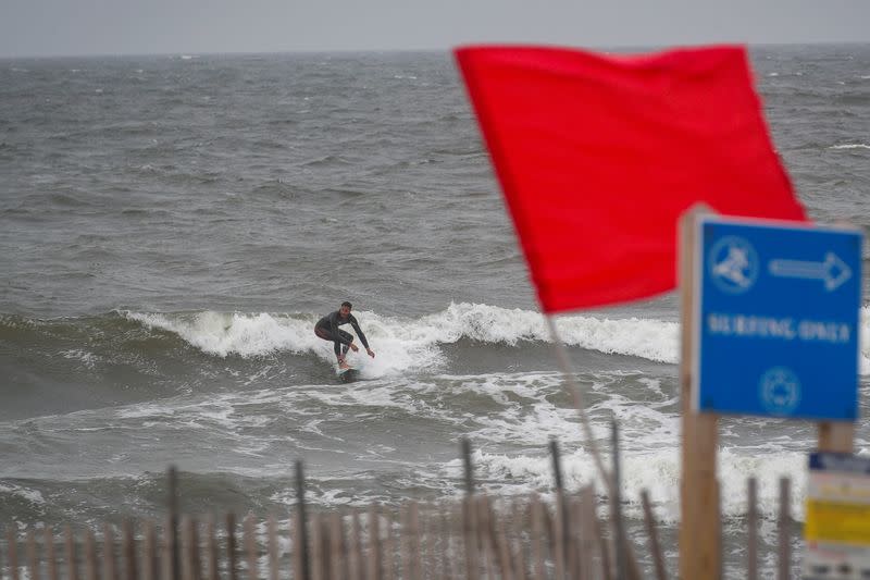 A surfer enjoys the surging surf ahead of Tropical Storm Isaias in the Rockaway area of Queens in New York