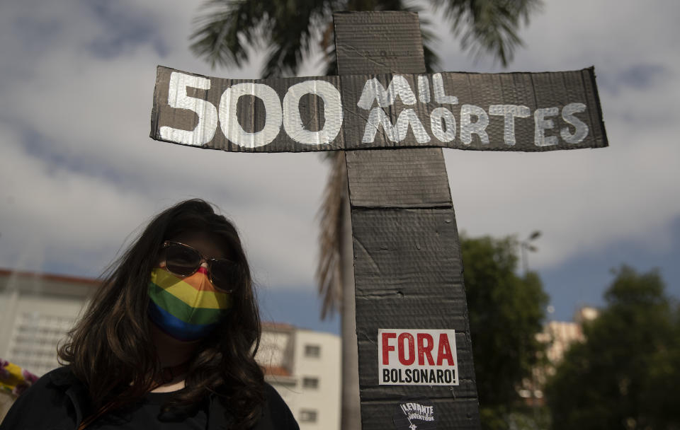 A woman, wearing a protective face mask, holds a sign in the shape of a cross with a message that reads in Portuguese;"500 k deaths", during a protest against Brazilian President Jair Bolsonaro and his handling of the pandemic and economic policies protesters say harm the interests of the poor and working class, in Cuiaba, Brazil, Saturday, June 19, 2021. Brazil is approaching an official COVID-19 death toll of 500,000 — second-highest in the world. (AP Photo/Andre Penner)