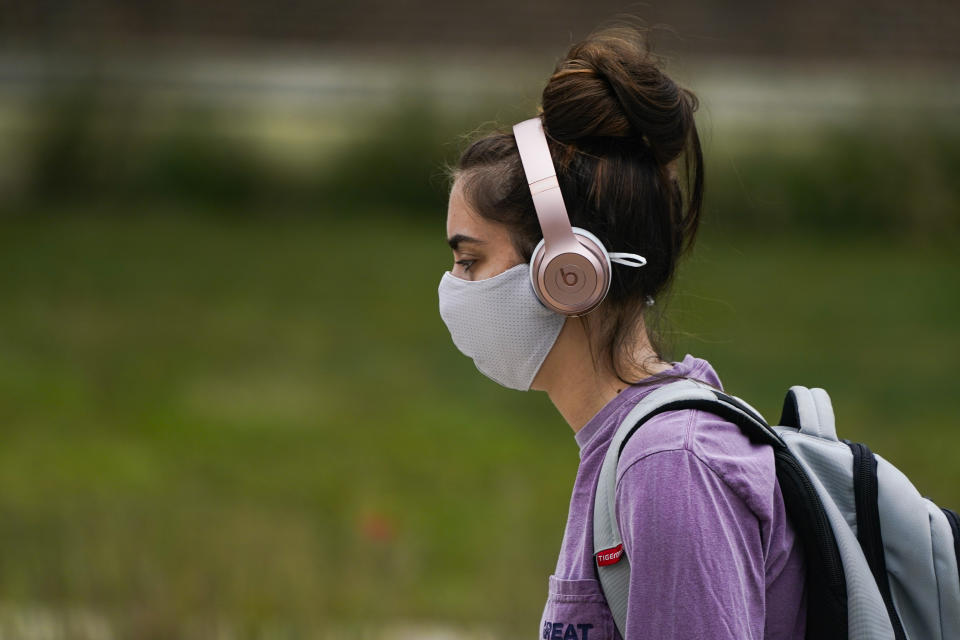 A masked student walks through the campus of Ball State University in Muncie, Ind., Thursday, Sept. 10, 2020. College towns across the U.S. have emerged as coronavirus hot spots in recent weeks as schools struggle to contain the virus. Out of nearly 600 students tested for the virus at Ball State, more than half have returned been found positive, according to data reported by the school. Dozens of infections have been blamed on off-campus parties, prompting university officials to admonish students. (AP Photo/Michael Conroy)