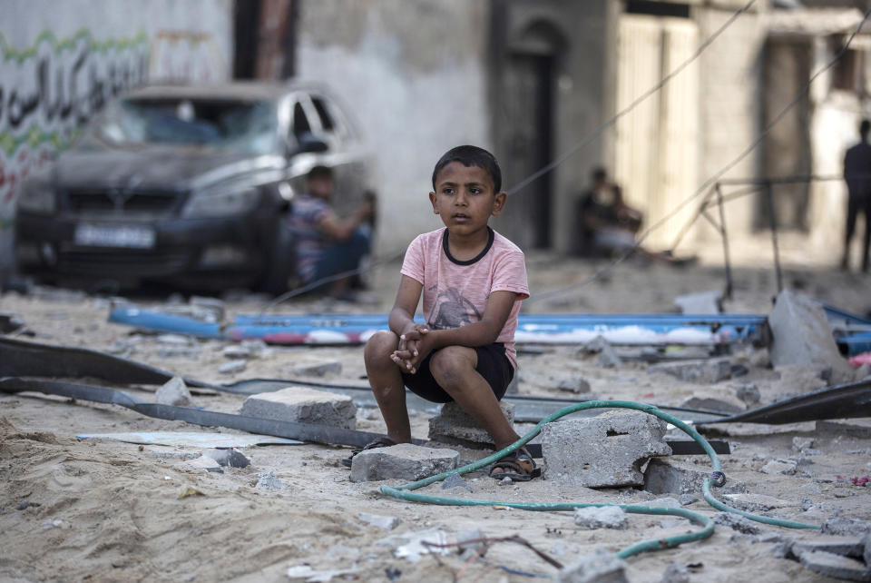 Image: A Palestinian boy sits looking at others inspecting the damage of their shops following Israeli airstrikes on Jabaliya refugee camp, northern Gaza Strip (Khalil Hamra / AP)
