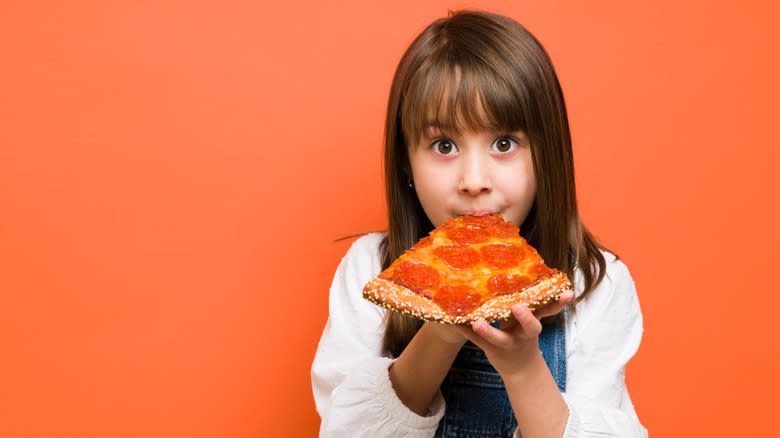  child eating slice of pizza