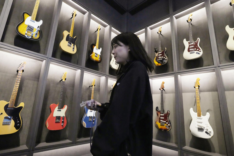 A staff member walks past Fender guitars on display at the opening ceremony of its Tokyo store Thursday, June 29, 2023. Fender, the guitar of choice for some of the world’s biggest stars from Jimi Hendrix to Eric Clapton, is opening what it calls its “first flagship store” in its 77-year history. (AP Photo/Eugene Hoshiko)