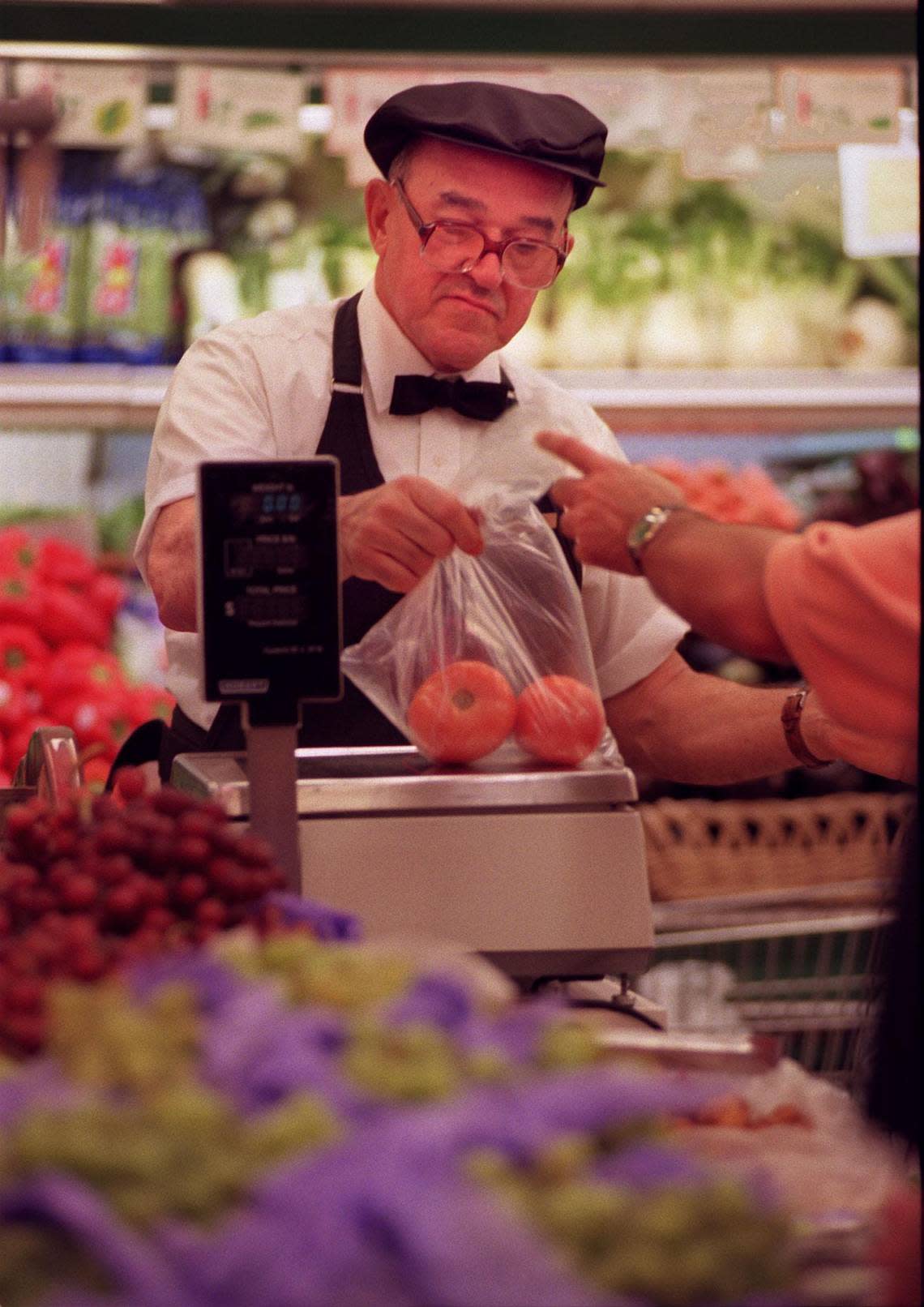 Epicure employee Alberto Serpa weighs tomatoes for a customer. Candace Barbot/Miami Herald File/1998