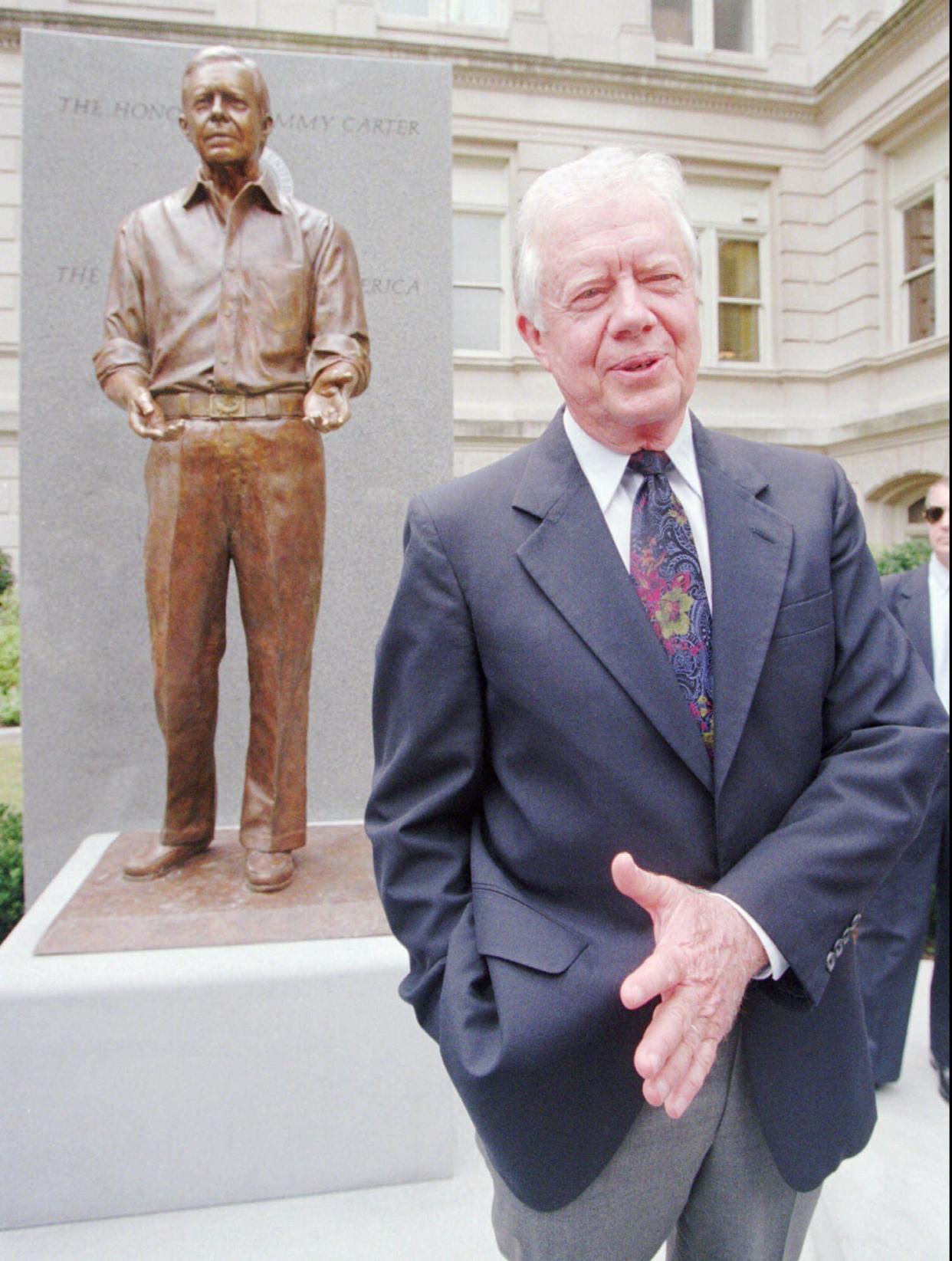 Former President Jimmy Carter speaks with reporters following the unveiling of a statue of him on the grounds of the Georgia State Capitol on June 7, 1994, in Atlanta. The sculpture, by Frederick Hart, shows former President Carter in an informal pose and casual dress with his sleeves rolled up, honoring his roots as a farmer.